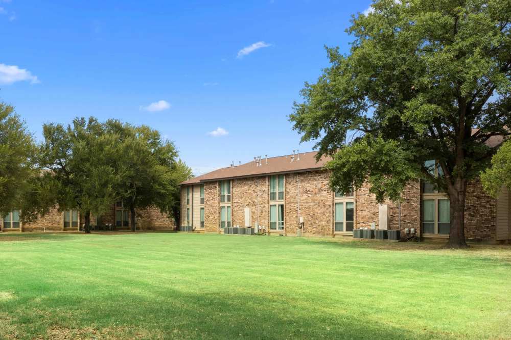 Exterior view of the apartment with green landscaping at Woodland Village Apartments in Breckenridge, Texas