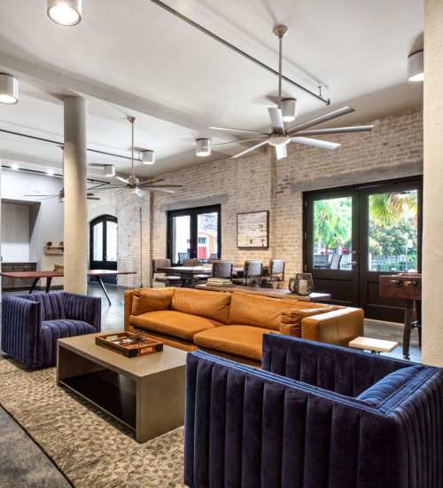 Modern lounge with stylish seating and fans at American Can Apartments in New Orleans, Louisiana