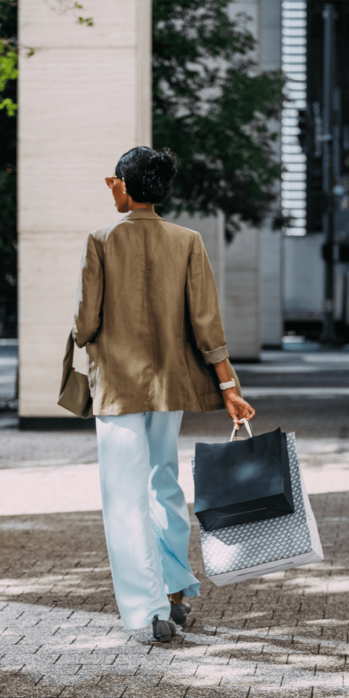 Stylish woman walking with shopping bags in urban setting at Residences at 111 Lyon in Grand Rapids, Michigan