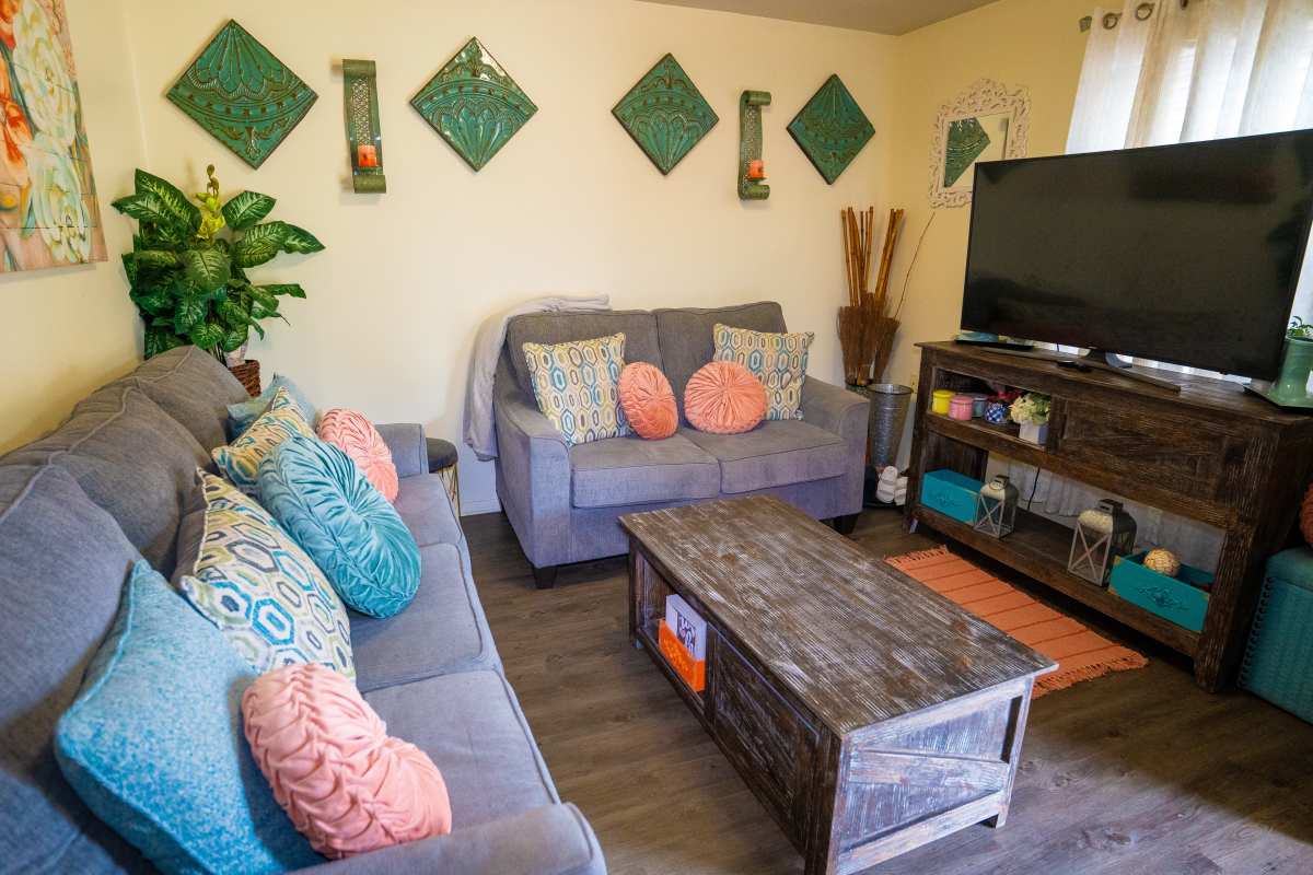 Cozy living room with wood-style flooring, plush sofas, decorative pillows, and a large TV at Willowbrook I in Lafayette, Louisiana