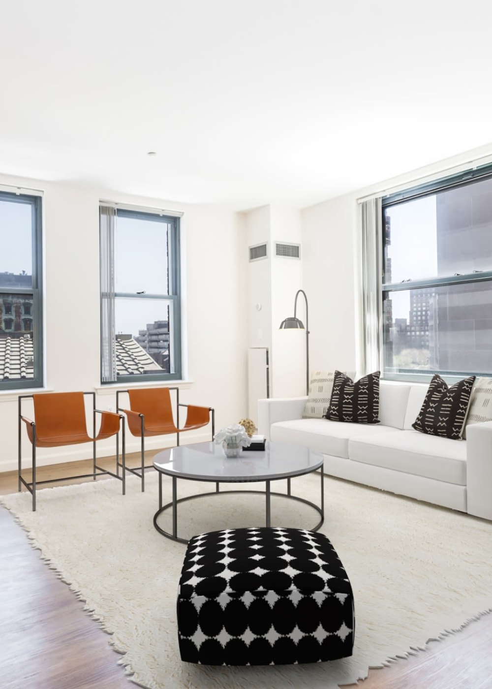 Apartment living room with large rug, sofa, and city views at One India Street Apartments in Boston, Massachusetts