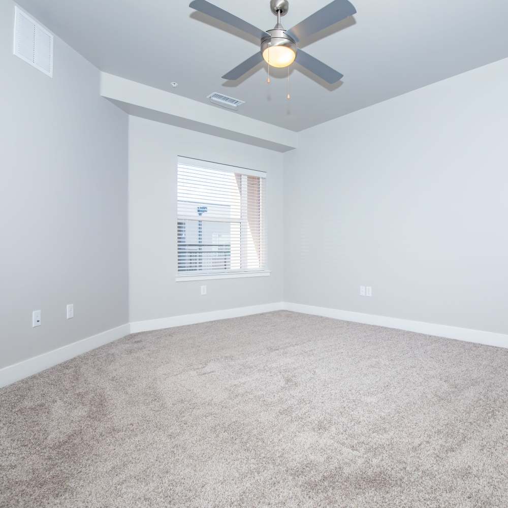 Bedroom with large window, ceiling fan and carpet flooring at Park Place Olde Town Apartments in Arvada, Colorado