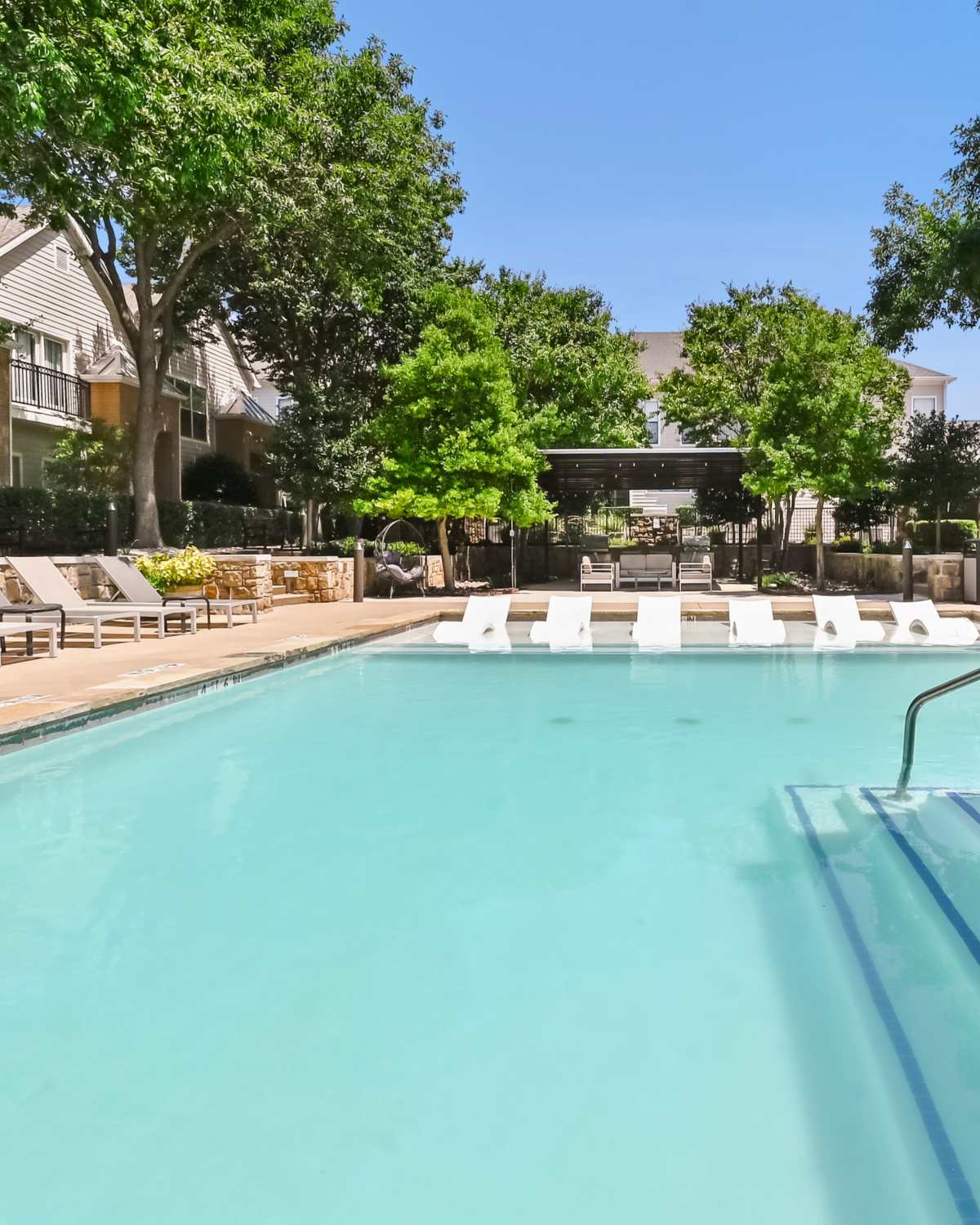 Lounge chairs in pool the park at Arbor Hills at Flatiron District at Austin Ranch in The Colony, Texas