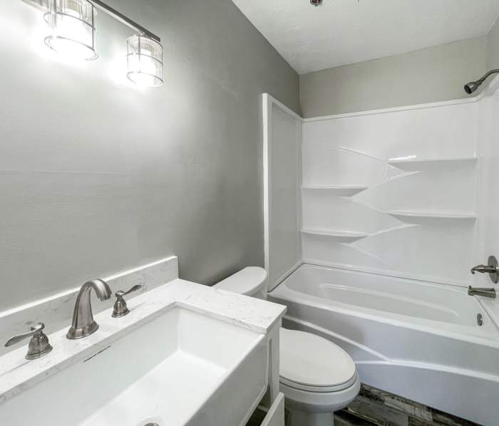 Bathroom with vanity light, sink, commode and standard bathtub at District on Bethel in Muncie, Indiana