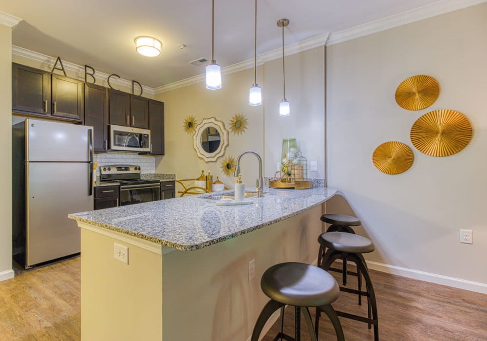 Kitchen island with light fixtures and bar stools on hard-wood style flooring at at Greymont Village in Asheville, North Carolina