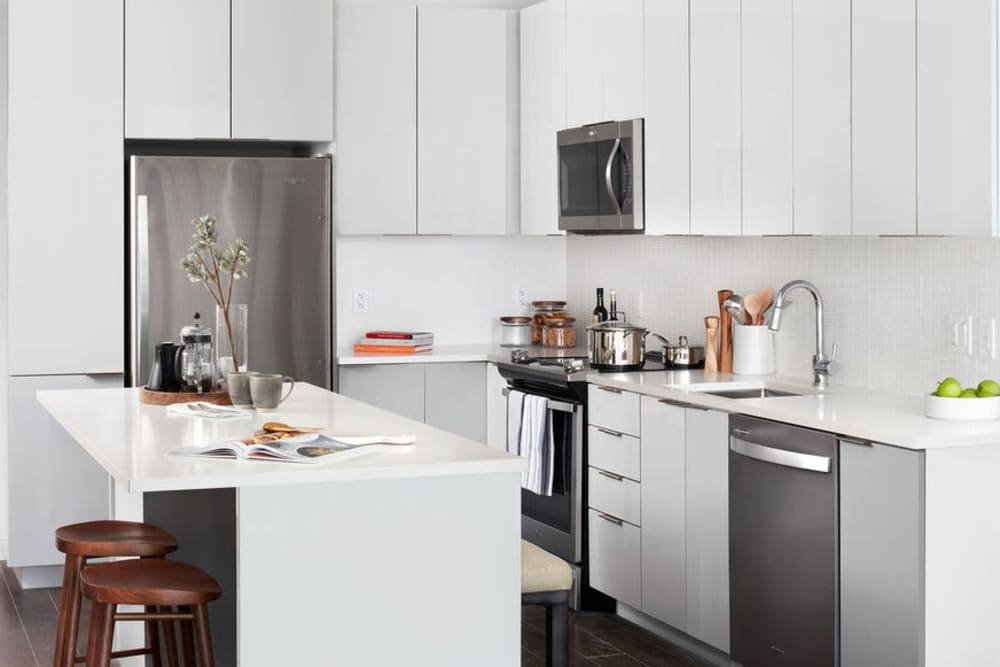 Fully-equipped kitchen with stainless steel appliances and island with bar stools at Ardan in Dallas, Texas