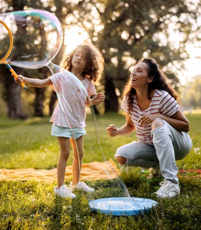 Resident and child blowing bubbles at Parkwood Oaks in Bedford, Texas