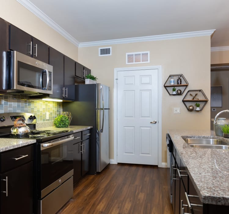 Dark wood cabinetry and a breakfast bar in a model home's kitchen at Hilltops in Conroe, Texas