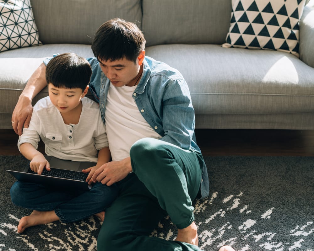 Resident student doing some homework on his laptop with help from his dad in their new home at Sofi at Forest Heights in Portland, Oregon