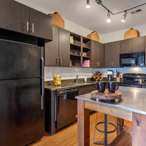 Model home's kitchen with an island and black appliances at Olympus Midtown in Nashville, Tennessee