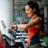 Fitness center with woman checking smartwatch at August Friendswood in Friendswood, Texas
