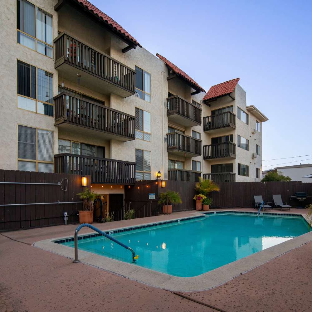 Gated apartment community featuring a sparkling pool and balconies on upper floors at Villa Capri in San Diego, California