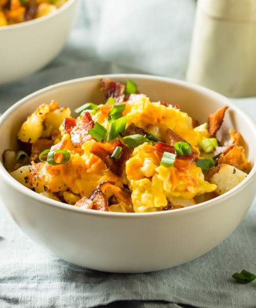 Bowl of scrambled eggs with bacon, cheese, and green onions on a light blue tablecloth at Brentnell Pointe in Columbus, Ohio