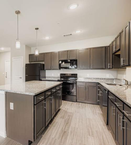 Upgraded kitchen with granite island and modern appliances at Standard at Royal Lane in Dallas, Texas