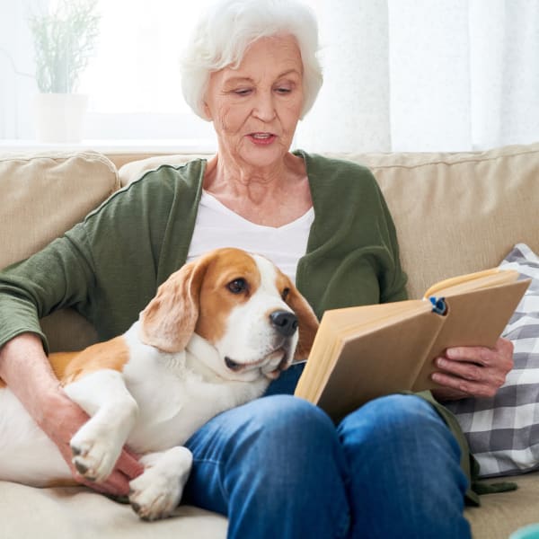 Woman with dog reading a book at Kenmore Senior Living in Kenmore, Washington