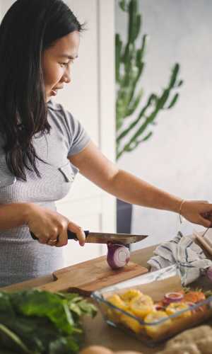 Resident preparing a meal in her new kitchen at Fisher Duplexes in Dallas, Texas
