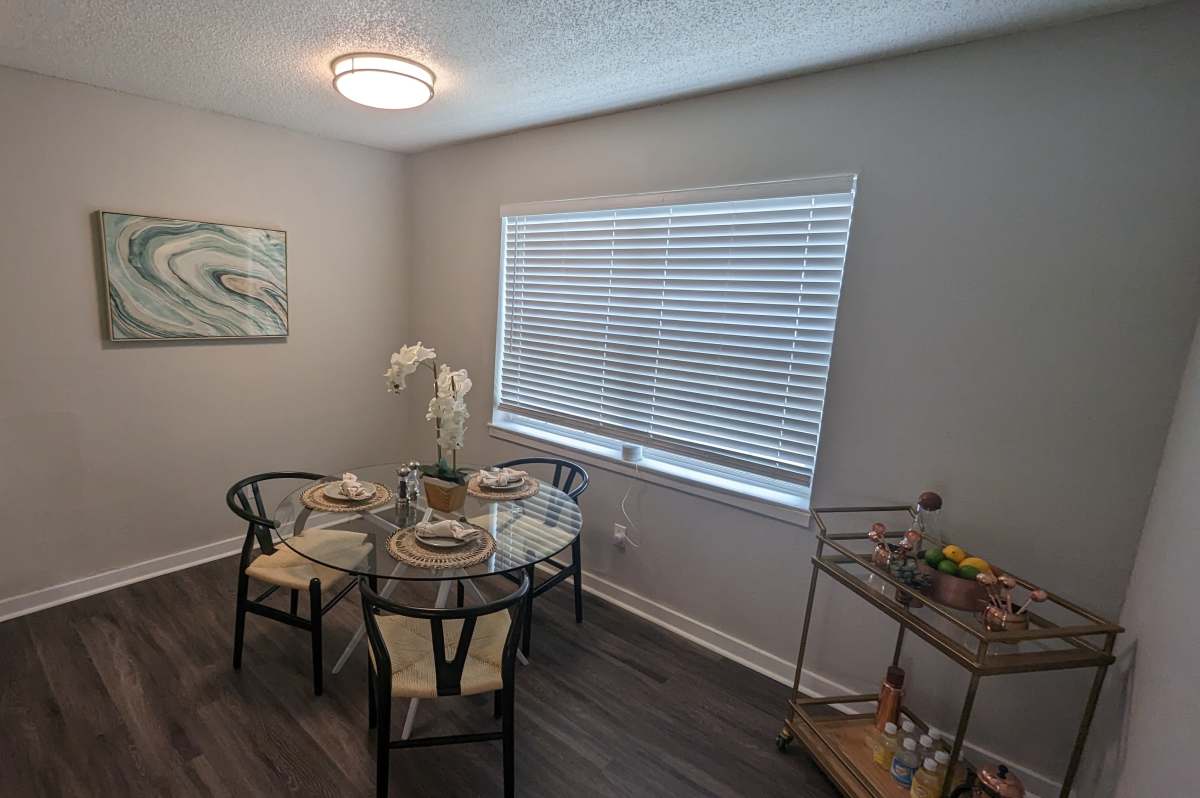 Austin, TX, Apartments for Rent - Sangria Park - A Modern Dining Area with a Round White Table, Gold Geometric Base, and a Trio of Blue and Green Abstract Paintings.