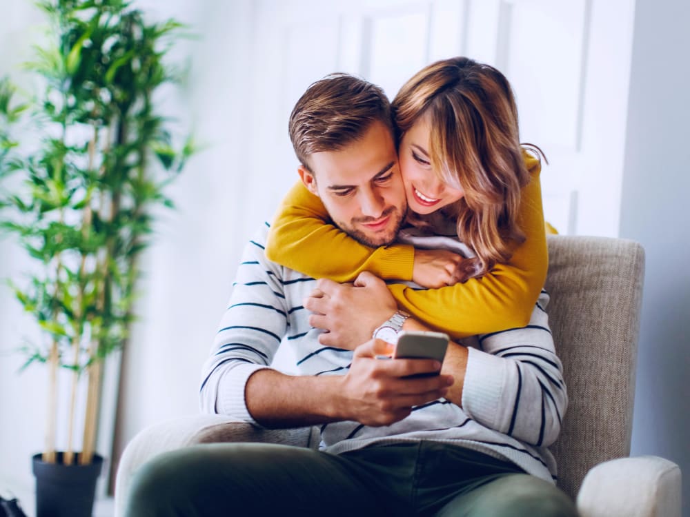 Resident couple checking information on smart phone at Terra Apartment Homes in Federal Way, Washington