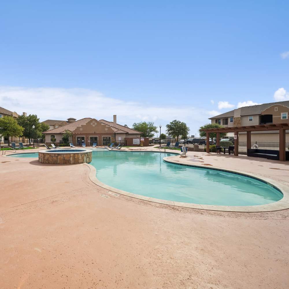 View of pool and hot tub with pergola and office in background at Sunset Lodge in Odessa, Texas