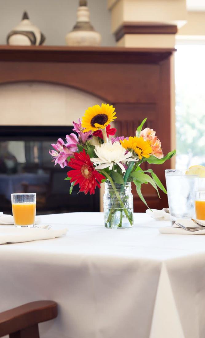 Vase of flowers on a set table in community dining room with fireplace at Dougherty Ferry in Valley Park, Missouri