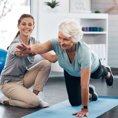 A woman doing a fitness routine with an instructor at Milestone Retirement Communities