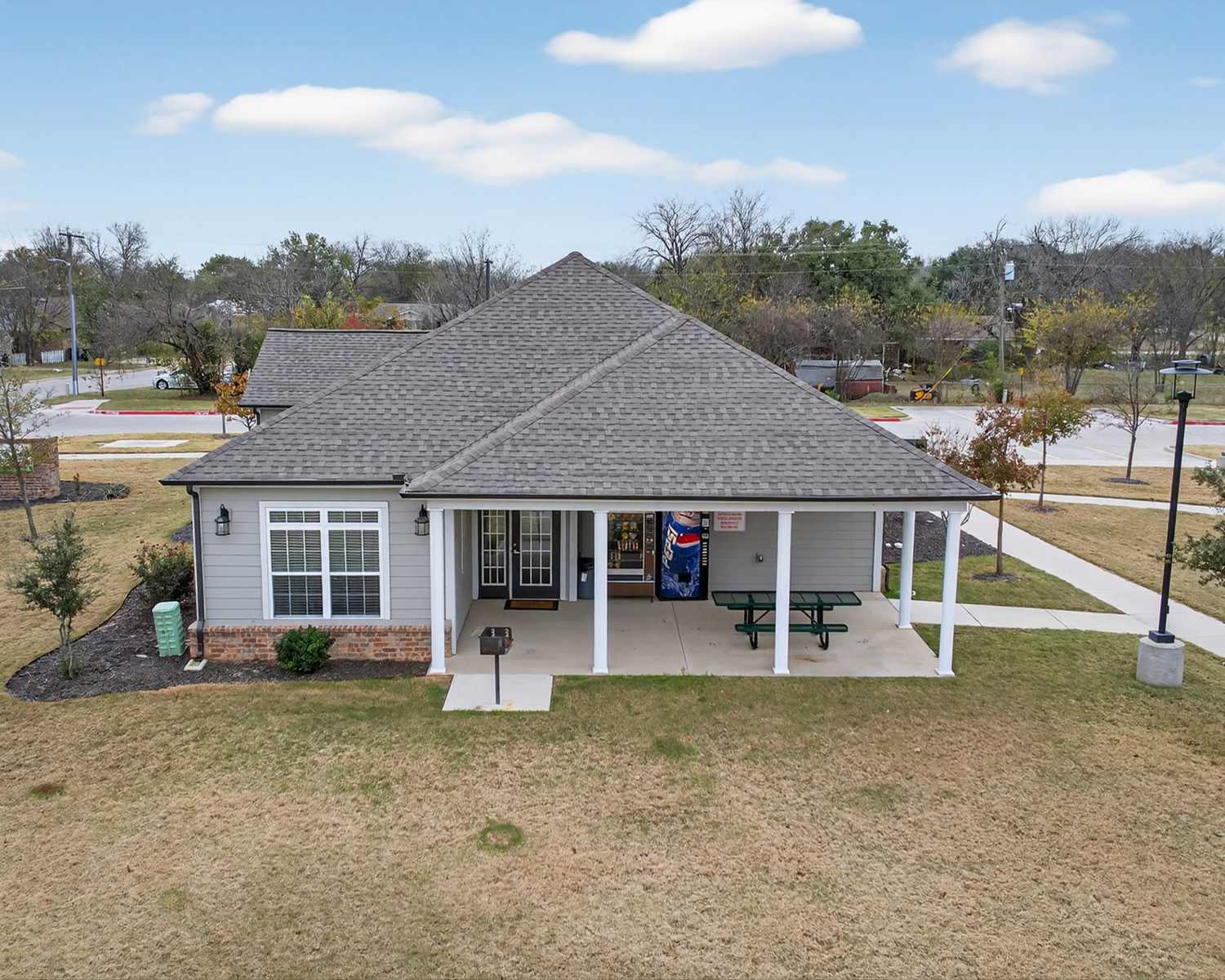 Charming community center with inviting outdoor seating and lush landscaping at Lakewood Crossing in Granbury, Texas.