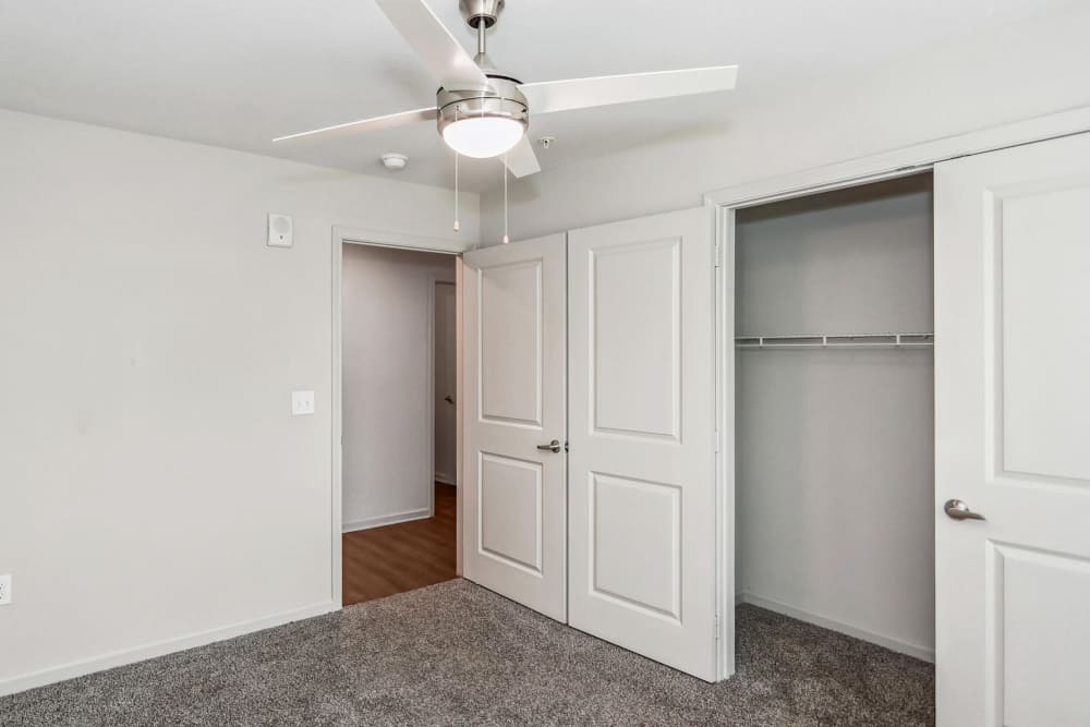 An unfurnished bedroom with access to the walk-in closet and a ceiling fan at Flats at Mount Zion in Stockbridge, Georgia