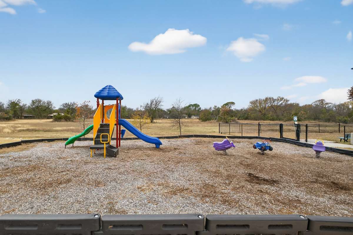 Vibrant playground featuring a colorful slide and spring riders at Lakewood Crossing in Granbury, Texas.