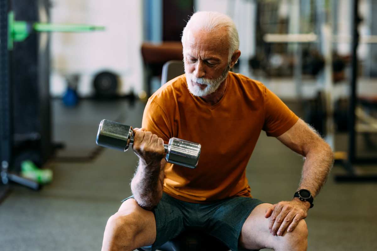 Senior man lifting dumbbell in a gym setting at Villas At Meadow Springs in Ankeny, Iowa