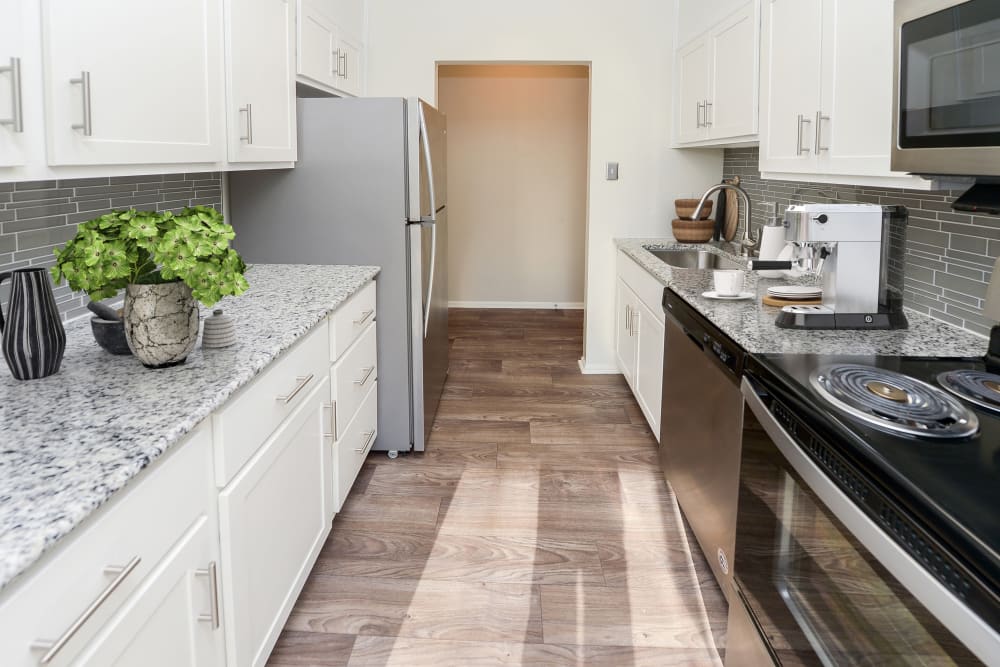 Renovated kitchen with white cabinetry and vinyl plank flooring at King's Manor Apartments in Harrisburg, Pennsylvania