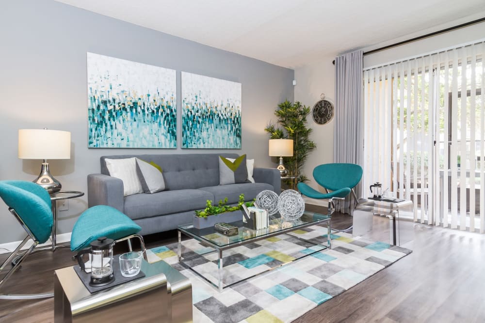 Model apartment living room with wood-style flooring opening onto a private patio at Central Place at Winter Park in Winter Park, Florida