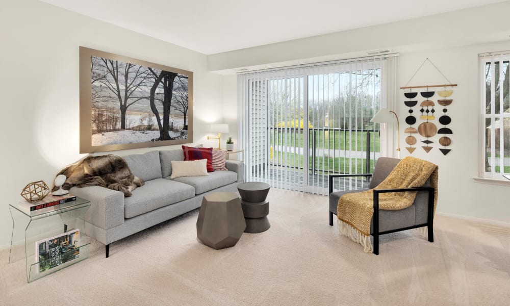 Model living room with eclectic modern decor and private patio access at Fairmont Park Apartments in Farmington Hills, Michigan