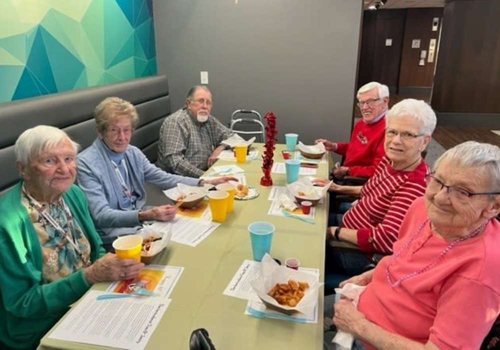 Resident friends eating a meal together at a long dining table at Turners Rock in Springfield, Missouri