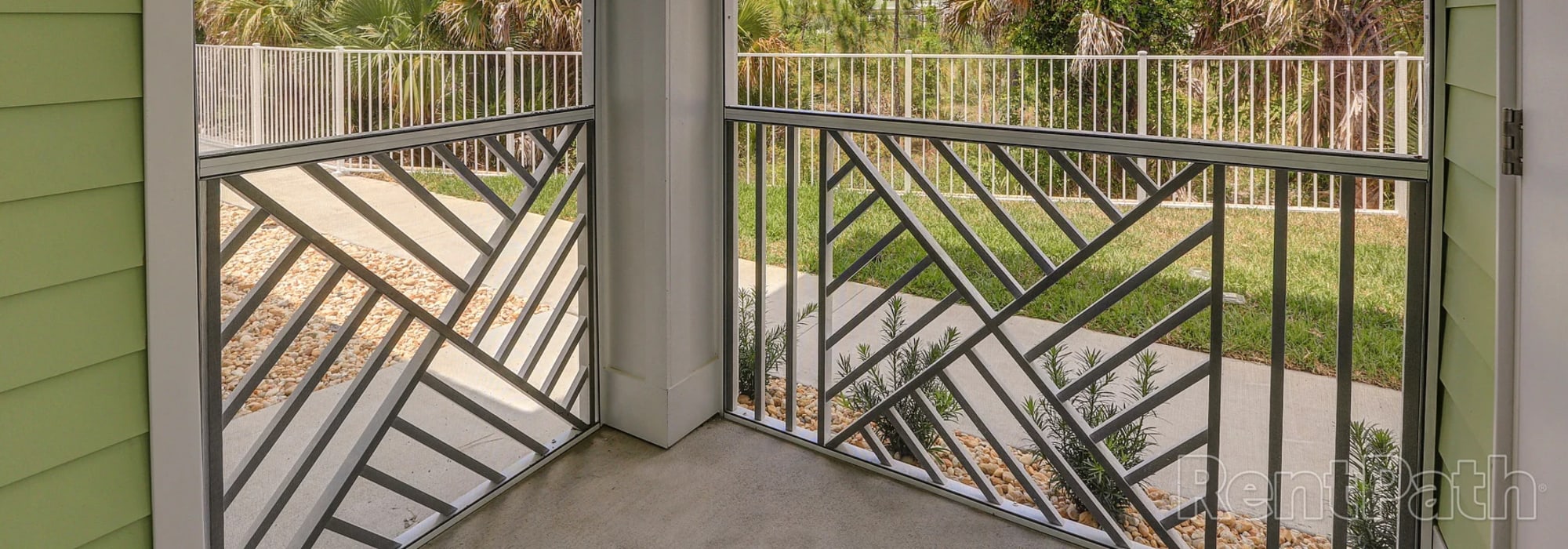 Charming outdoor space with lush landscaping and modern railing detail at Lemon Bay Apartments in Englewood, Florida
