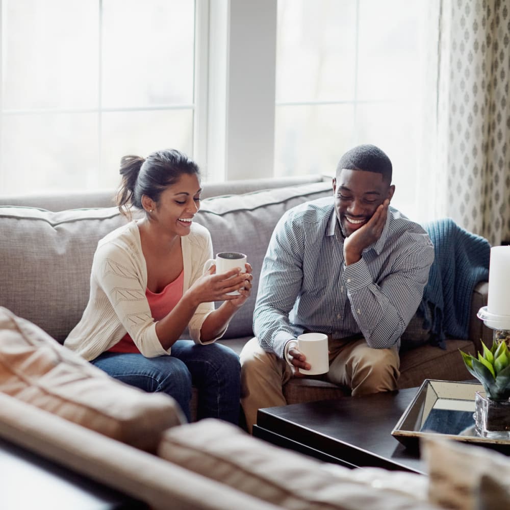 Resident couple chatting over morning coffee in their apartment at Oaks 5th Street Crossing At City Center in Garland, Texas