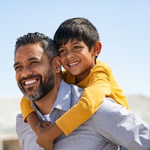 Smiling resident carrying his happy child on his back at Castle Hill in Sherman, Texas