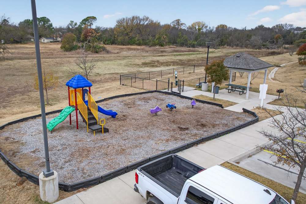 Vibrant playground with colorful equipment and shaded picnic area at Lakewood Crossing in Granbury, Texas.