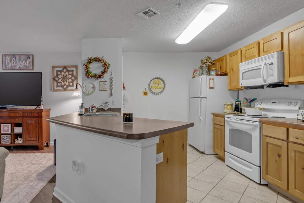 Kitchen with white appliances, wood cabinet and granite countertop at River Ridge in Sand Springs, Oklahoma