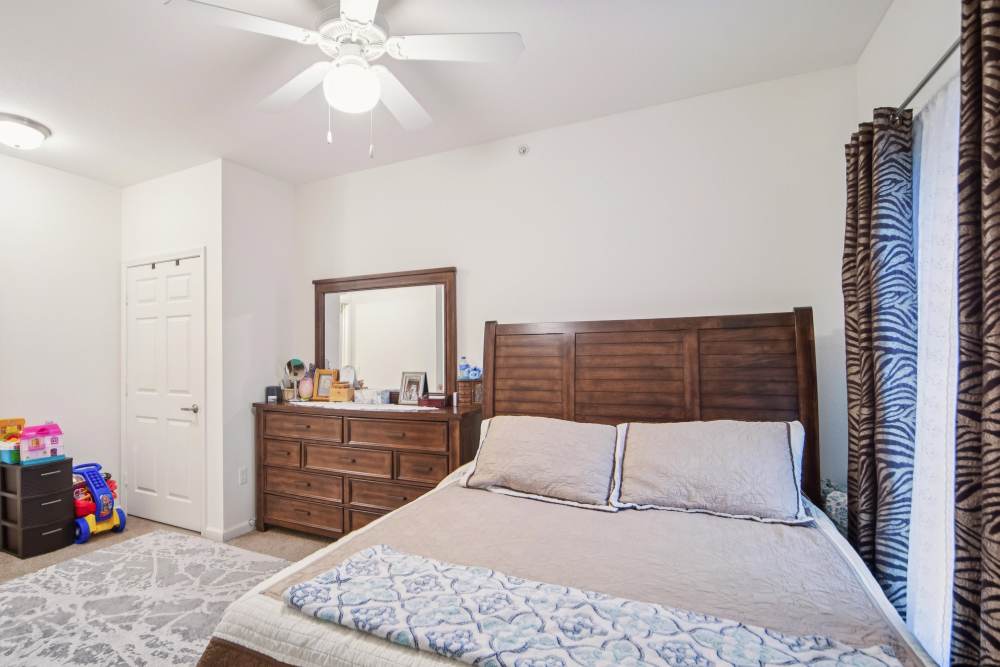 Cozy bedroom with wooden furniture and natural light at Villas At Meadow Springs in Ankeny, Iowa