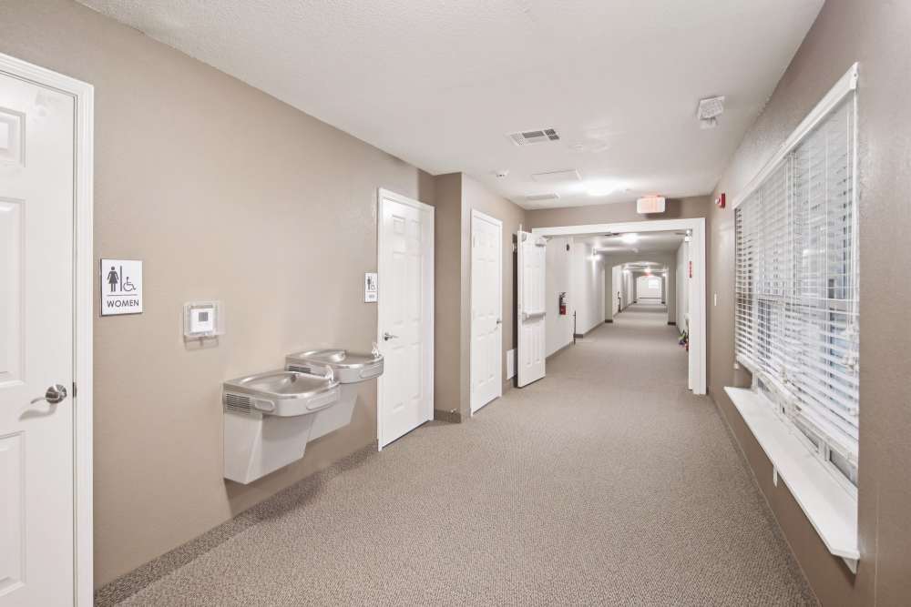 Clean hallway with restroom signs and water fountains at Villas At Meadow Springs in Ankeny, Iowa