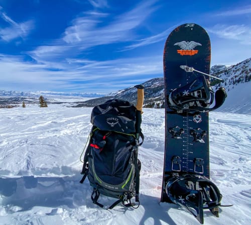 snow gear and snowboard sitting in the snow