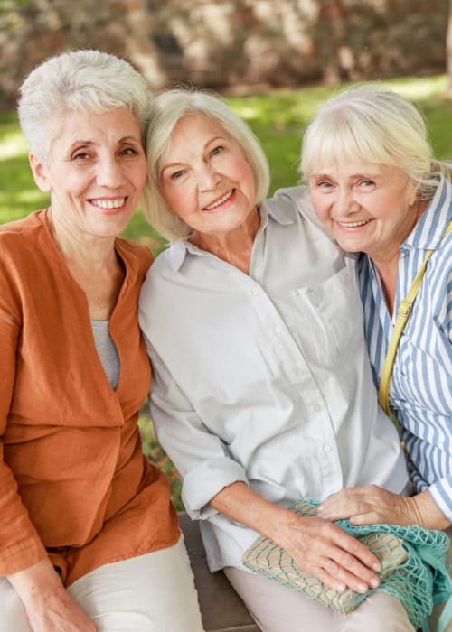 Trio of senior women smiling outdoors at The Pillars of Hermantown in Hermantown, Minnesota