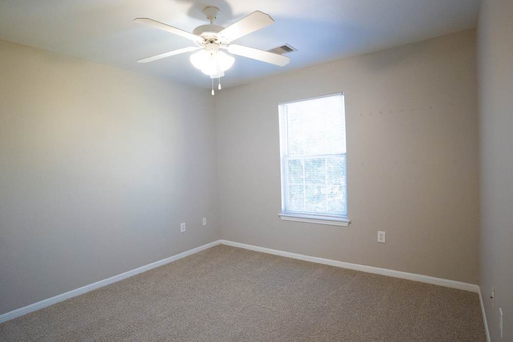 Ceiling fan and carpet flooring in bedroom of townhome at Millpoint Townhomes in Henderson, Texas
