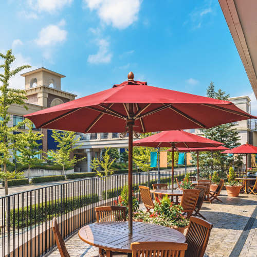 Outdoor dining area with umbrellas and greenery at Jefferson Manor Townhomes in Fairport, New York