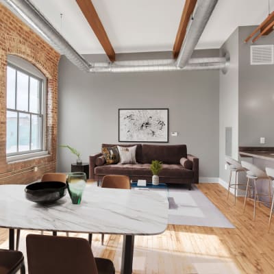 A bright, furnished living room with exposed brick at Barcalo Living in Buffalo, New York