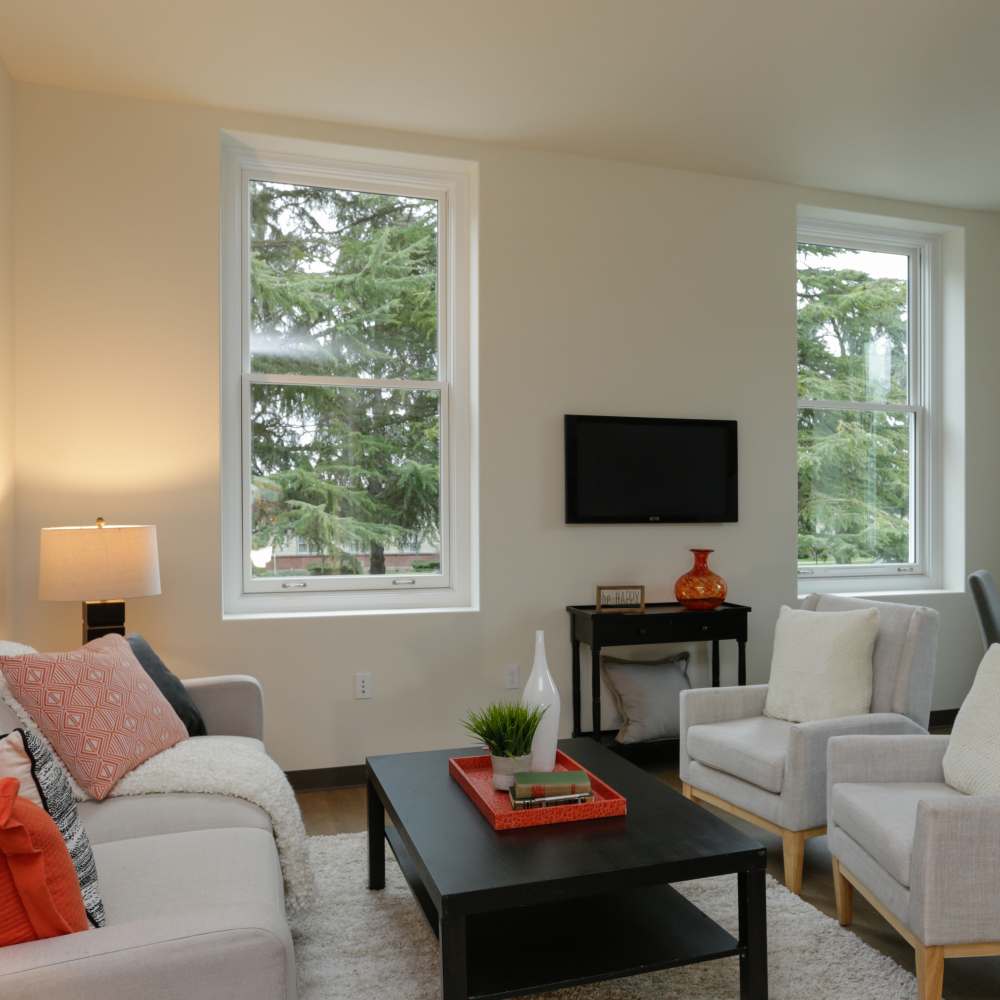 Clubhouse with sofa, wooden table with stools and television at Mercy Magnuson Place South in Seattle, Washington