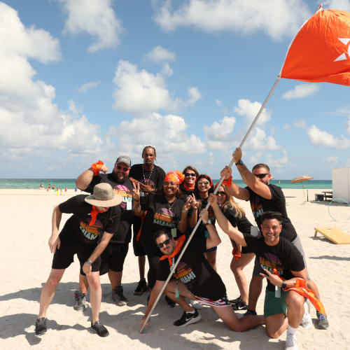 Employees posing for a team photo at an event on the beach at Campus Life & Style in Austin, Texas