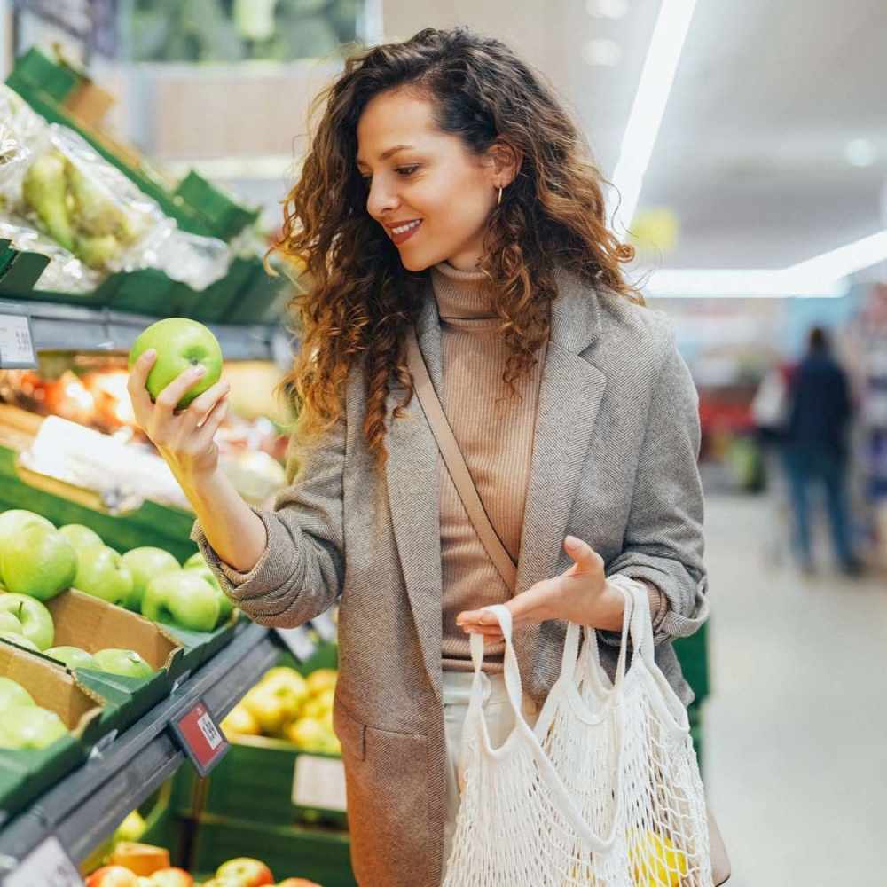 Woman holding a green apple in grocery store at Avia Lofts at Maple Road in Amherst, New York