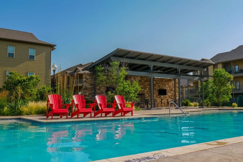 Red adirondack chairs by the resort-style pool at Anatole on MacArthur in Oklahoma City, Oklahoma
