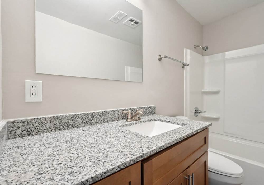 Bathroom with vanity lights bath tub and a commode at Charleston Square Apartments in Columbus, Indiana